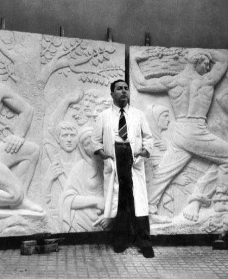 O artista junto aos relevos integrantes do Monumento Nacional ao Imigrante